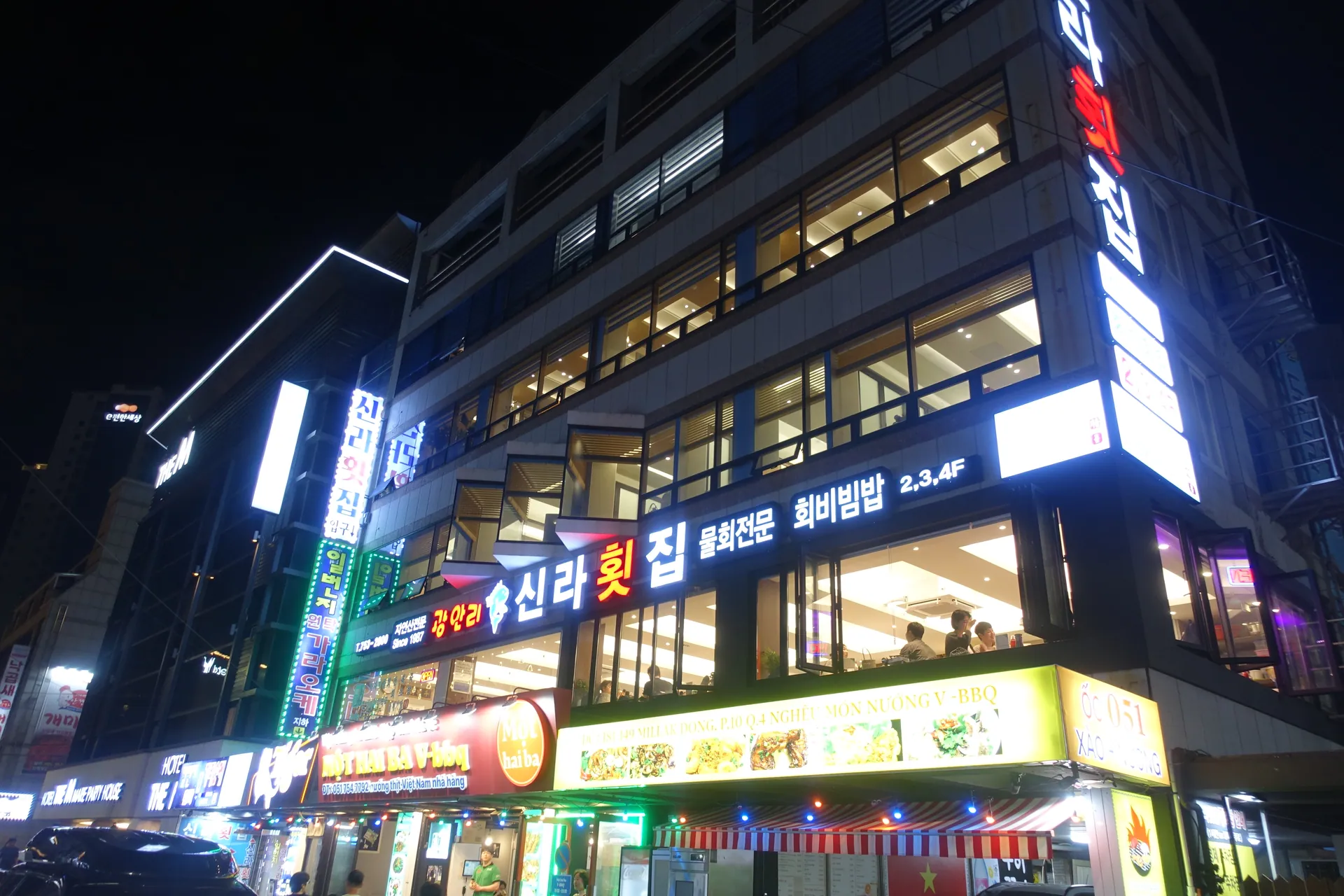 Exterior view of 광안리 신라횟집 with its name sign visible at night.