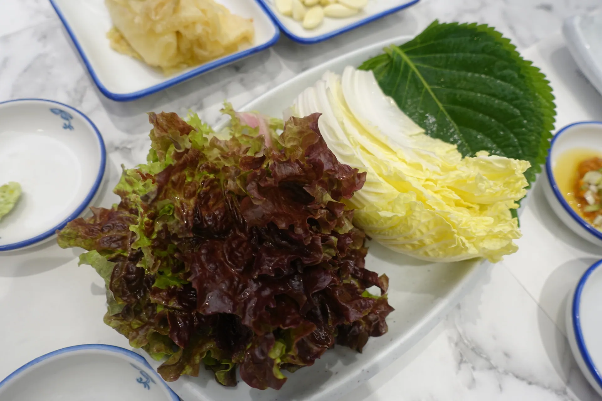 Fresh wrap vegetables and sides served at 광안리 신라횟집.